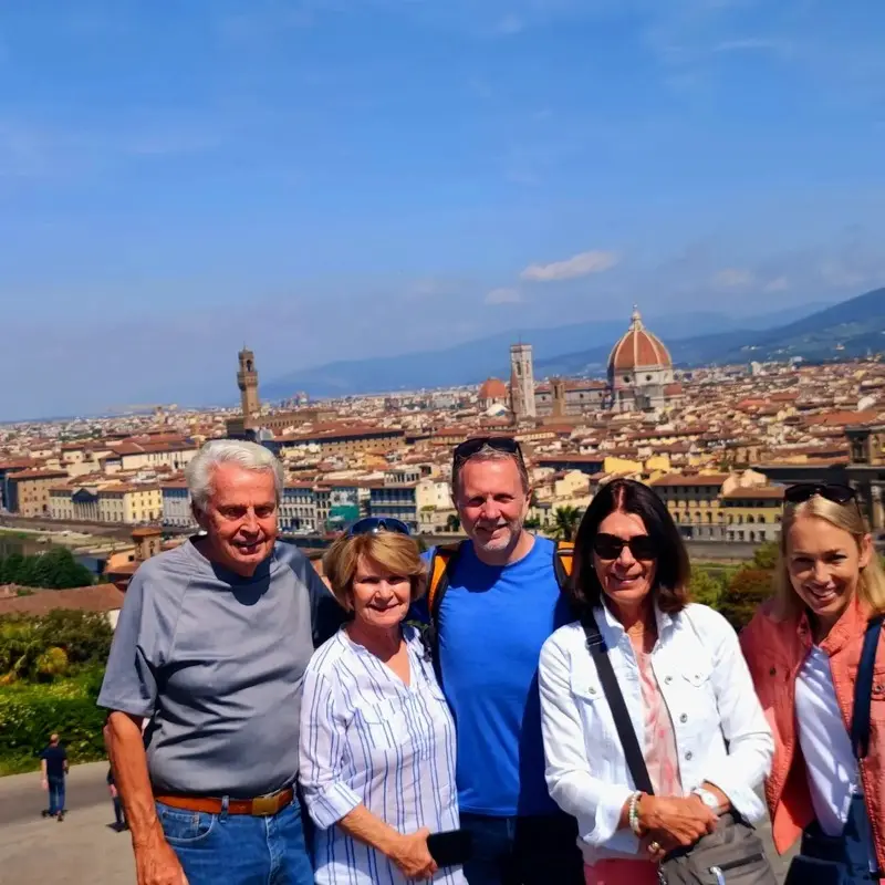 Group tour with scenic view of Florence, Italy: Five tourists posing for a photo with the Florence skyline, including the Duomo, in the background. Ideal for promoting guided tours and sightseeing in Florence.