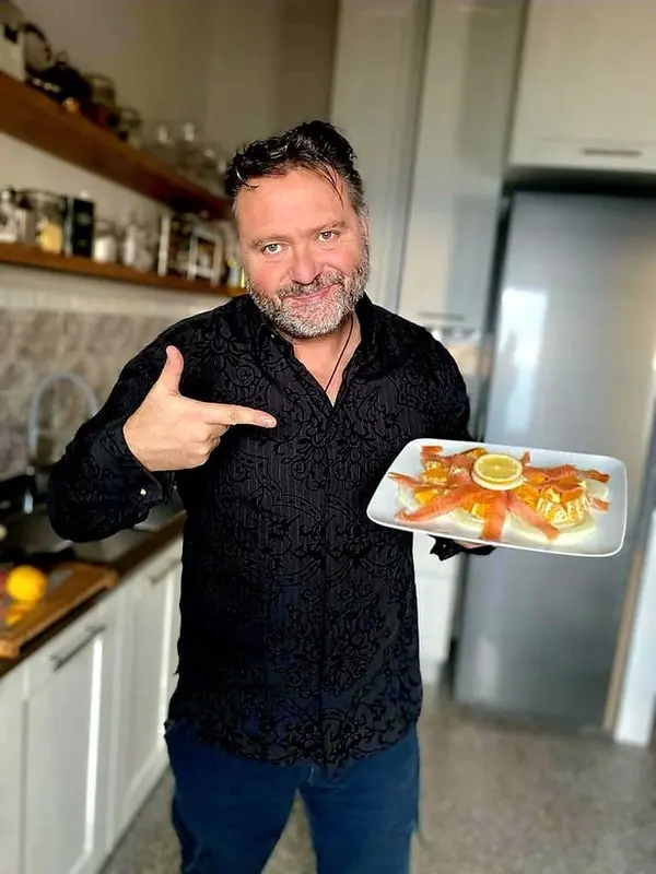 Fabrizio presenting Orange Fennel Salmon main course in Montepulciano: Fabrizio points to a plate of Orange Fennel Salmon, showcasing the main course from his private dinner served after a tour in his home. Ideal for promoting private dining experiences and culinary tours with Fabrizio in Montepulciano.