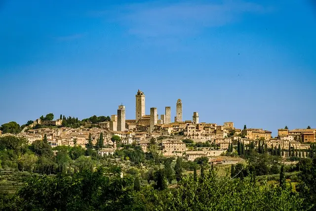 San Gimignano skyline, Tuscany: A panoramic view of the medieval hill town with its iconic towers against a clear blue sky. Ideal for promoting tours of San Gimignano and Tuscan cultural heritage.