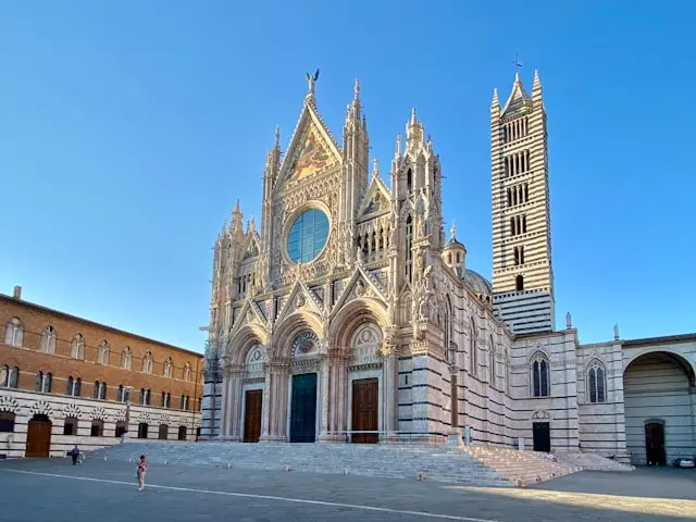 Siena Cathedral (Duomo di Siena), Tuscany, Italy: A stunning Gothic cathedral with intricate white and dark striped marble facade and a tall bell tower. Architectural landmark and popular destination for Siena sightseeing and cultural tours.